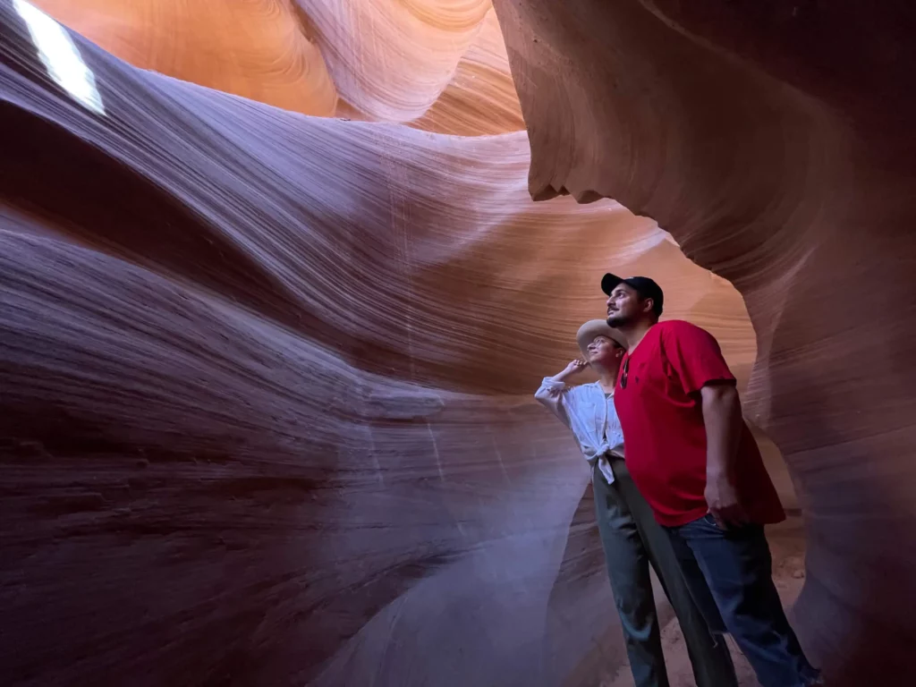 A couple in the Antelope Canyon in Arizona looking at the orange rocks.